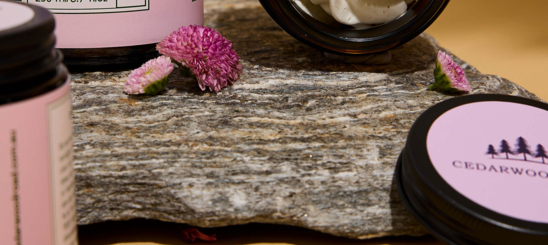 Cosmetic products with pink labels on a stone surface